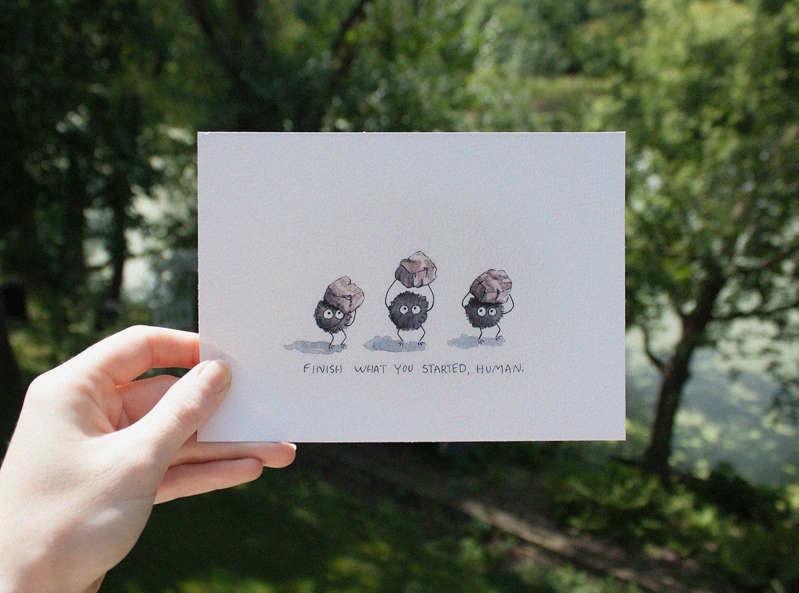 a watercolor with three soot sprites holidng rocks over their hands and the words &quot;finish what your started, human&quot; under them