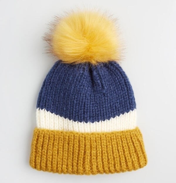 The gold, white, and blue striped beanie with a bright yellow pom pom