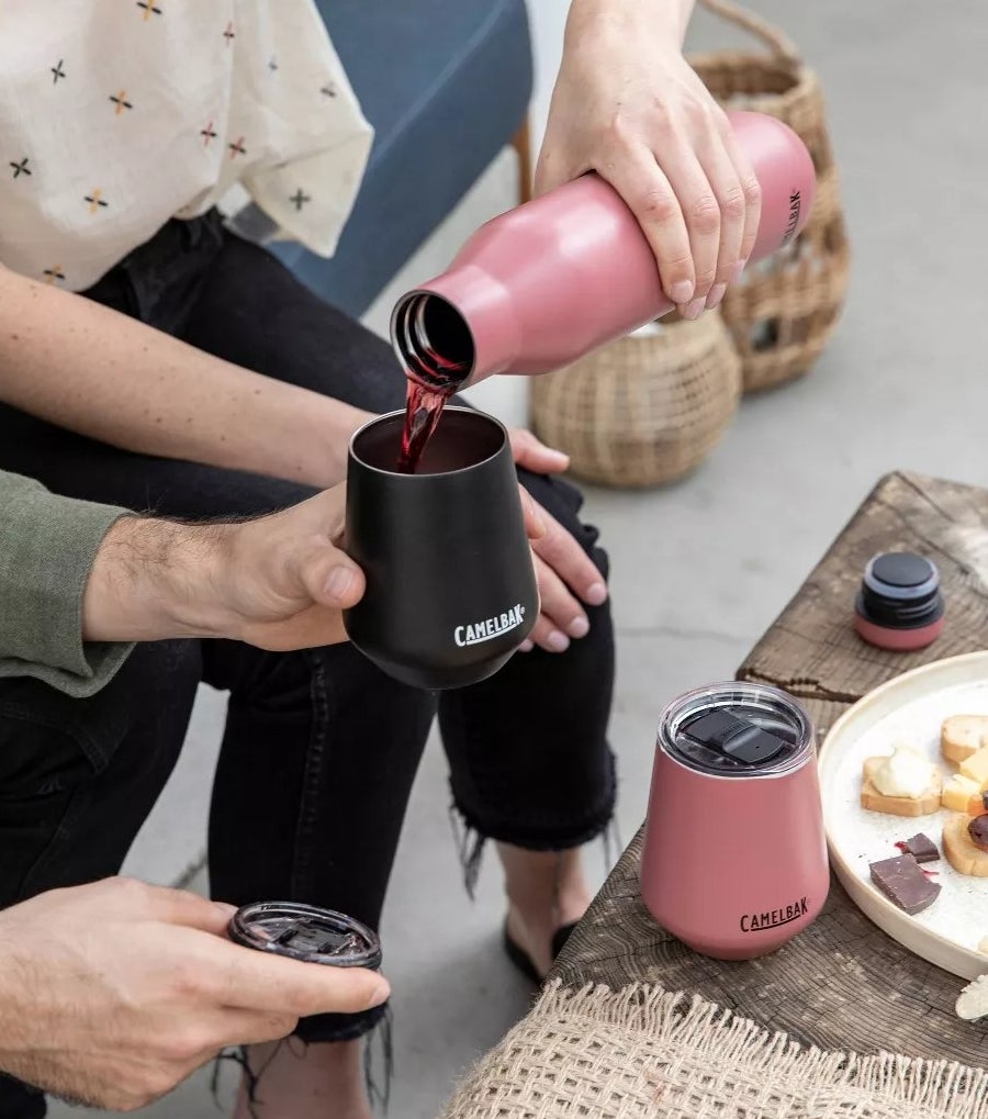 A model pouring red wine out of the pink Camelbak bottle