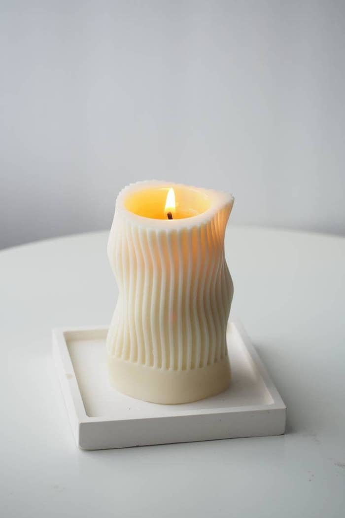 an off white beeswax candle with a wavy design