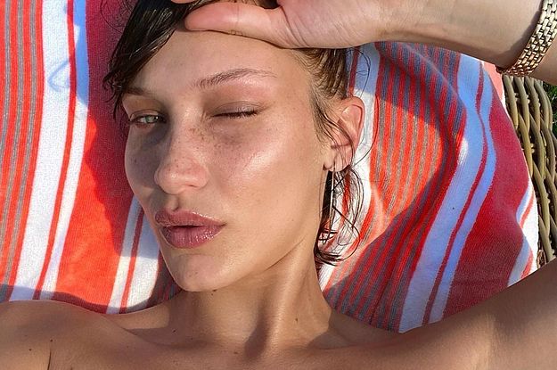 Bella Hadid squinting her eyes lying on a chair