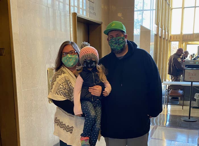 A family wearing masks stands near a security desk at the courthouse