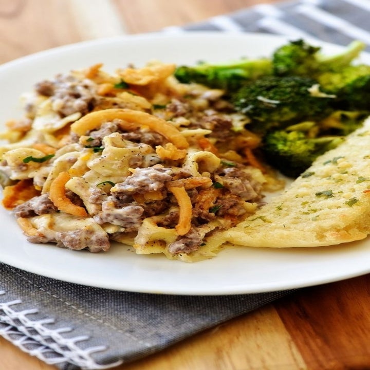 A plate with French onion beef casserole, potatoes, and broccoli on the side.