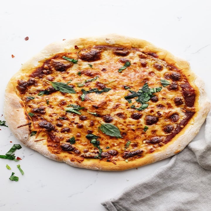 A cast iron skillet pizza with cheese, tomato sauce, and basil.