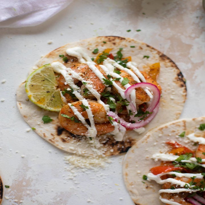 Two tortillas topped with shrimp and veggies and crema.