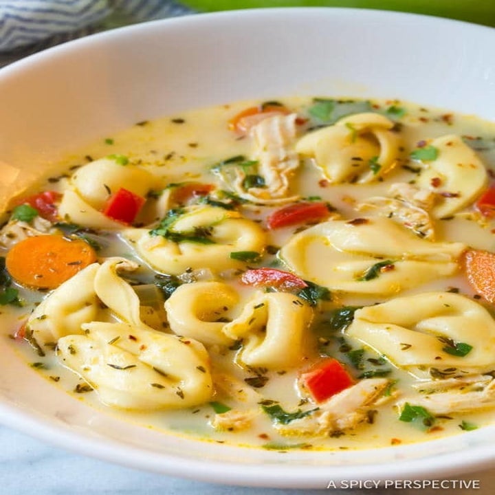 A bowl of creamy chicken tortellini and vegetable soup.
