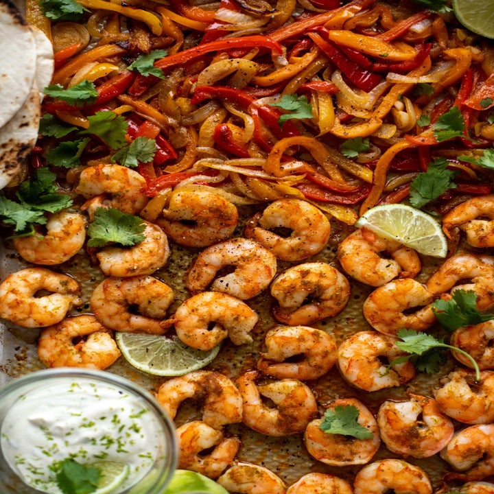 Shrimp and peppers and onion cooking on a sheet pan.