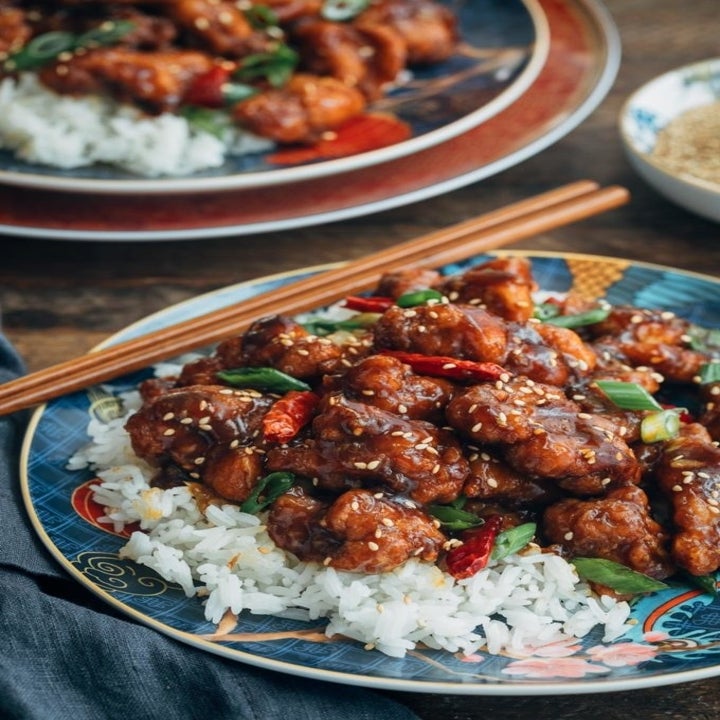 Two bowls of General Tso's chicken over white rice with chopsticks.