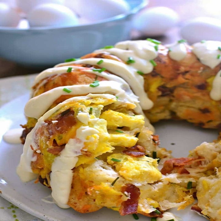 A bacon, egg, and cheese monkey bread loaf with sour cream sauce on top.