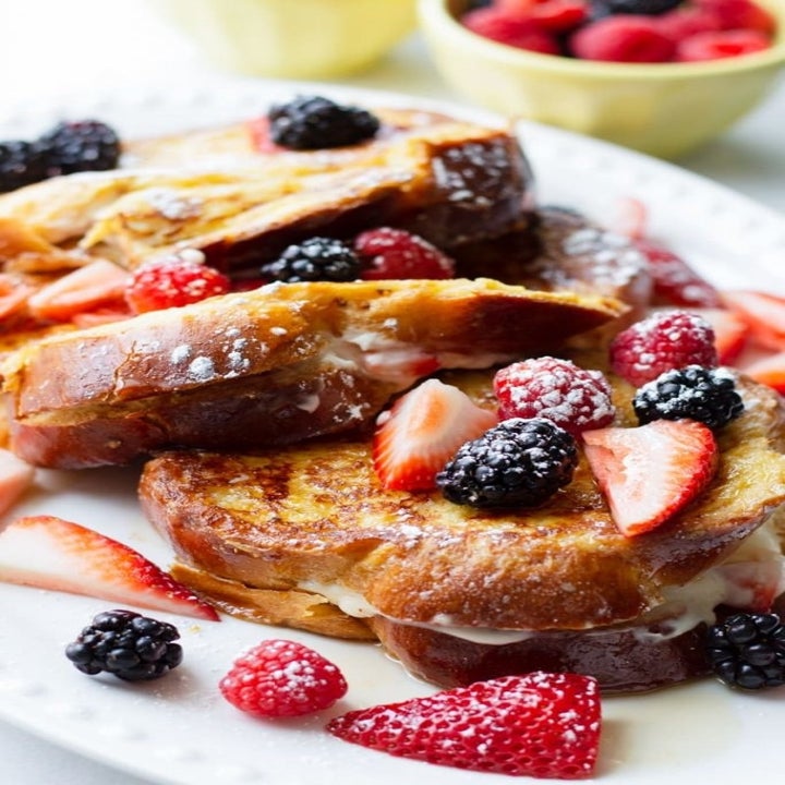 French toast topped with berries and stuffed with whipped cream filling.