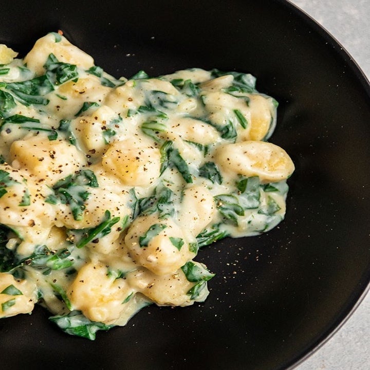 Gnocchi in spinach and Parmesan cream sauce on a plate.