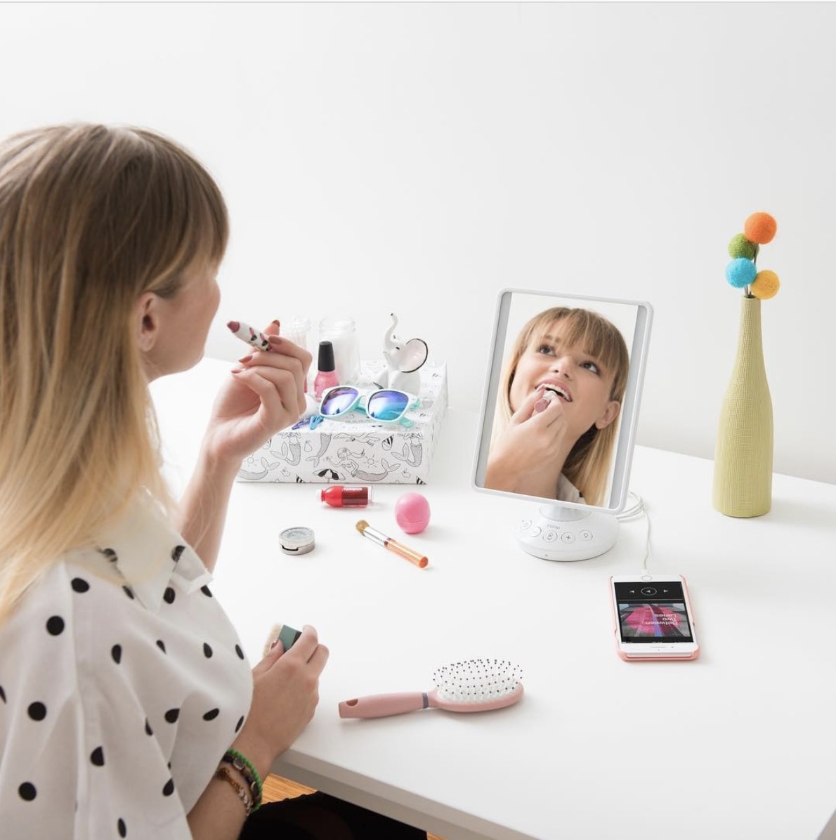 Person is applying makeup while looking into an iHome mirror
