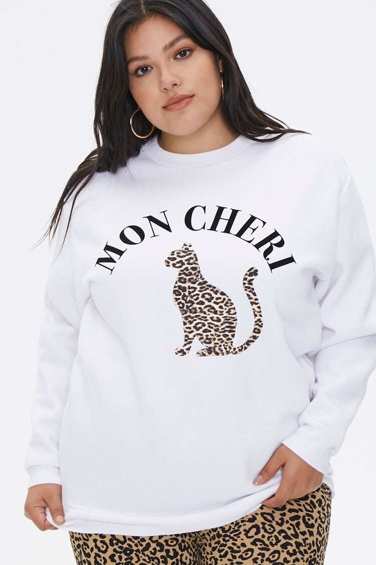 Model wearing the white pullover that has the graphic of a leopard and the text "Mon Cheri" on it