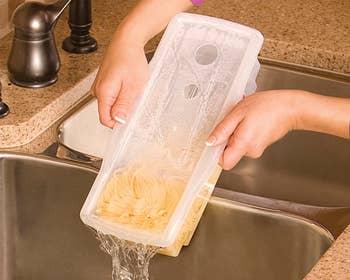 Water draining from clear Fasta Pasta container held over a silver sink