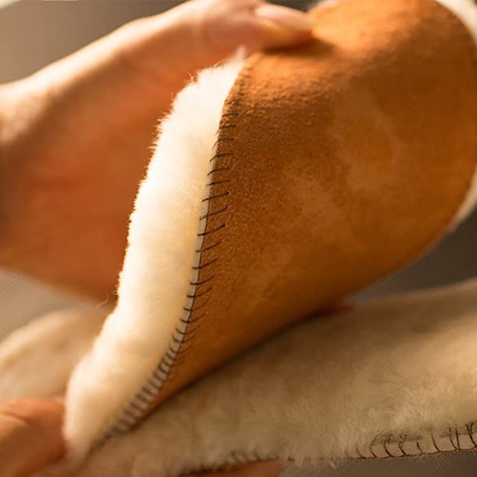 A person holding a pair of fluffy sheepskin insoles