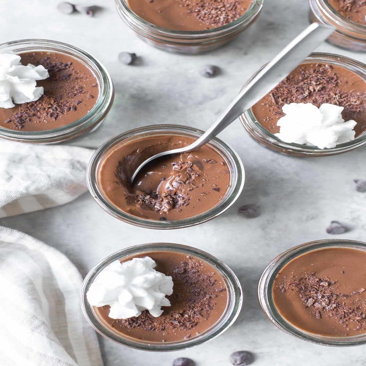 Several ramekins of chocolate pudding with whipped cream.