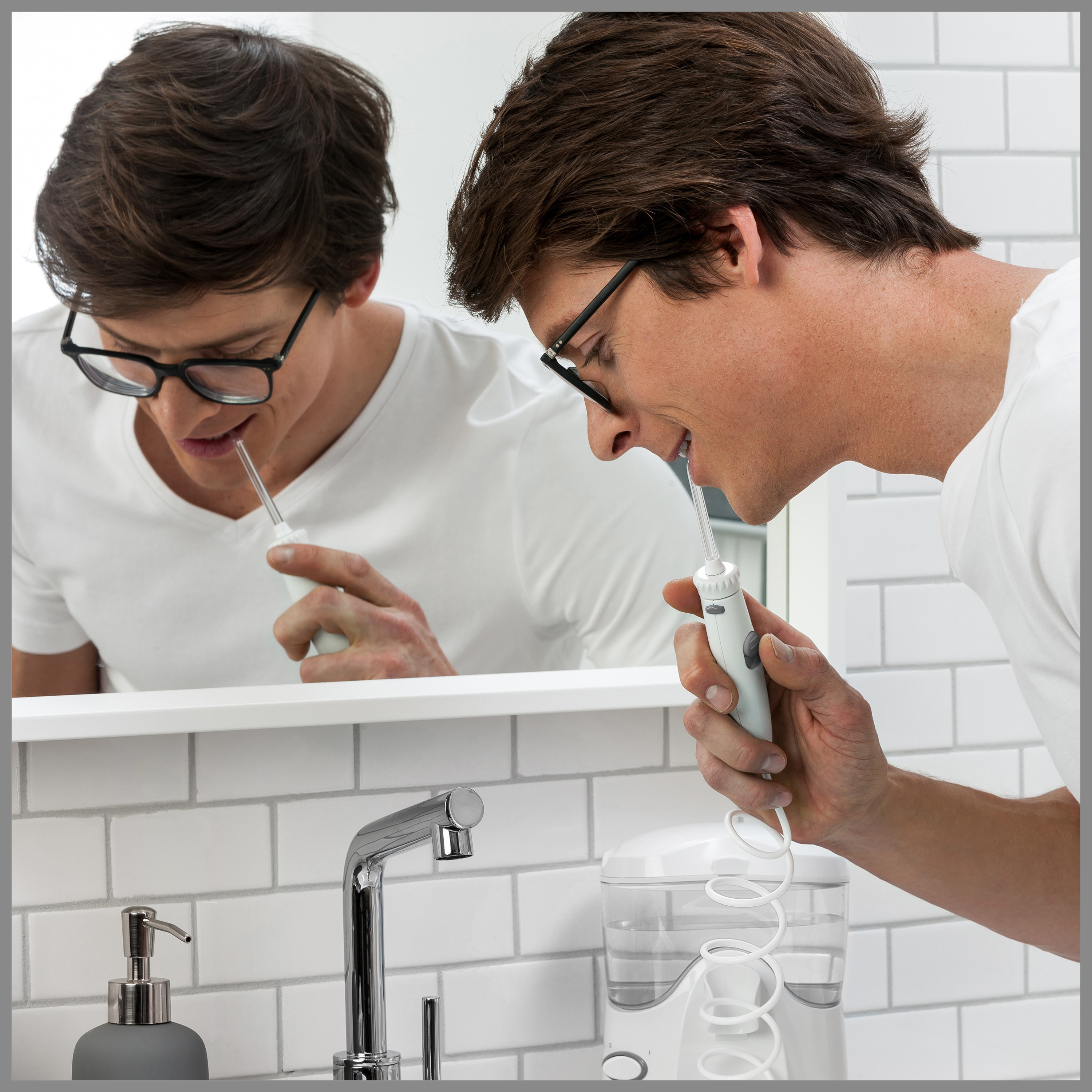 Model is flossing teeth with a water flosser in a bathroom