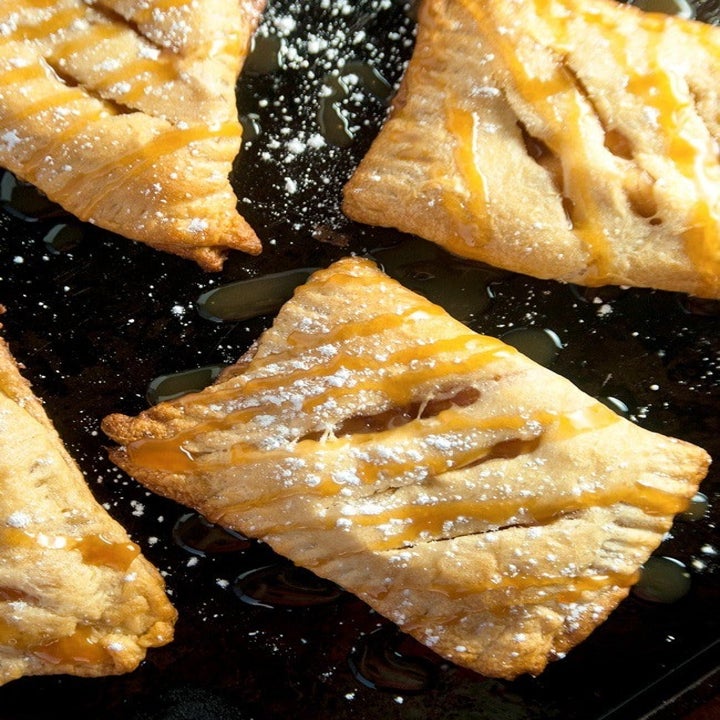 Four apple pie turnovers with powdered sugar.