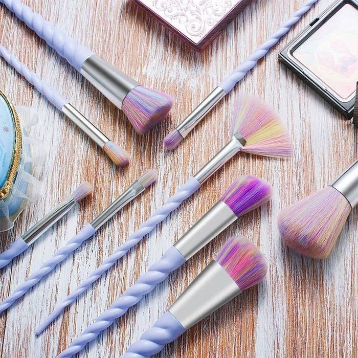 The brushes with purple unicorn-horn-looking twists for handles, silver metal connectors, and pastel yellow, pink, purple, and blue bristles