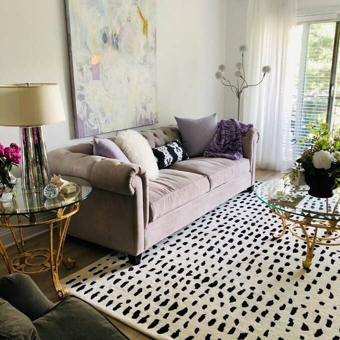 a white rug with black polka dots on a living room floor under a couch