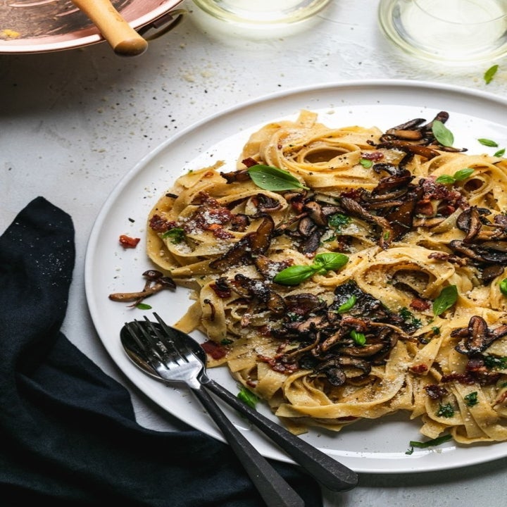 A plate of tagliatelle with crispy mushrooms in a creamy Parmesan and egg yolk sauce.