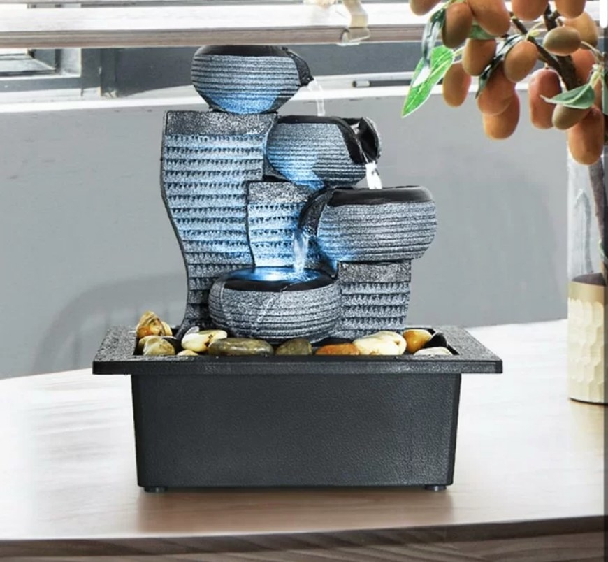 Gray and black tabletop waterfall with blue LED lights, water pouring into base with rocks