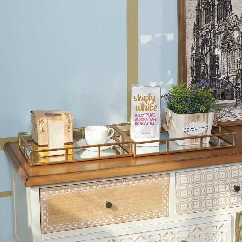 gold rectangular trays with mirrors at their base holding a coffee cup and milk 