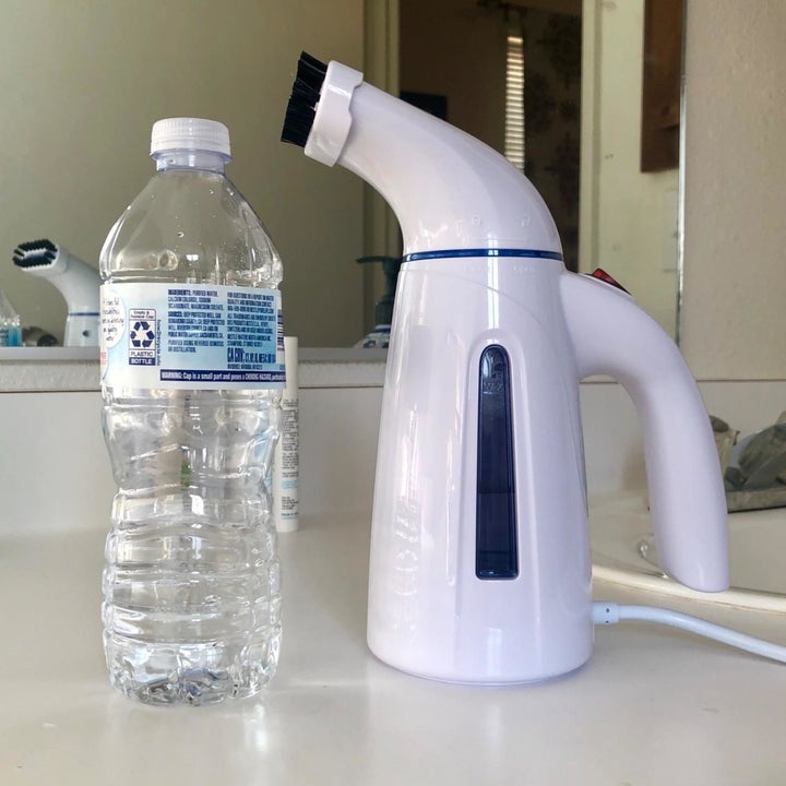 A reviewer's fabric steamer displayed upright next to a bottle of water