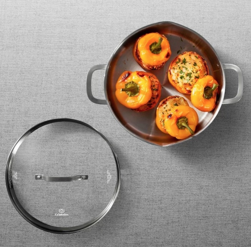 Stainless steel dutch oven pan with stuffed peppers inside, glass and steel ventilated lid on the side
