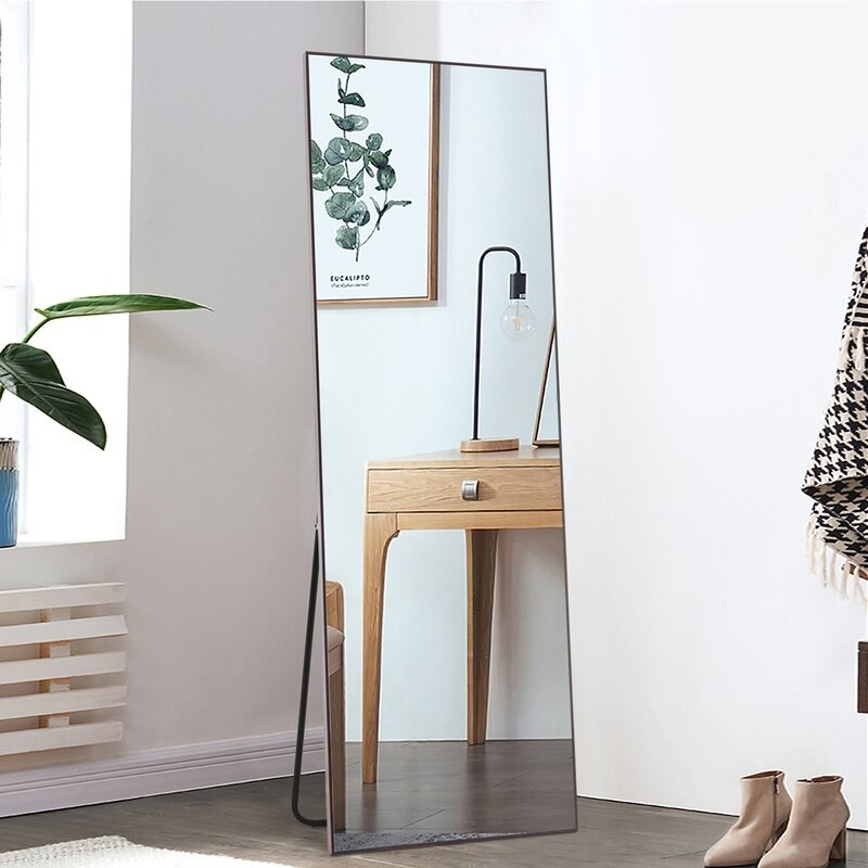a full length floor mirror with a stand and brown trimming