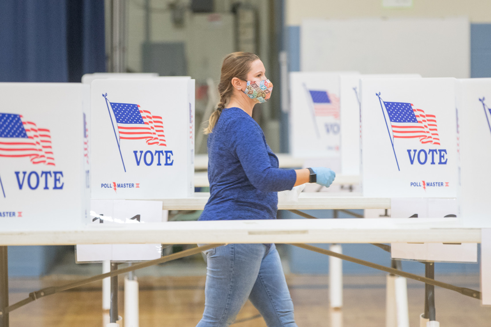 A poll worker walking by several empty voting booths