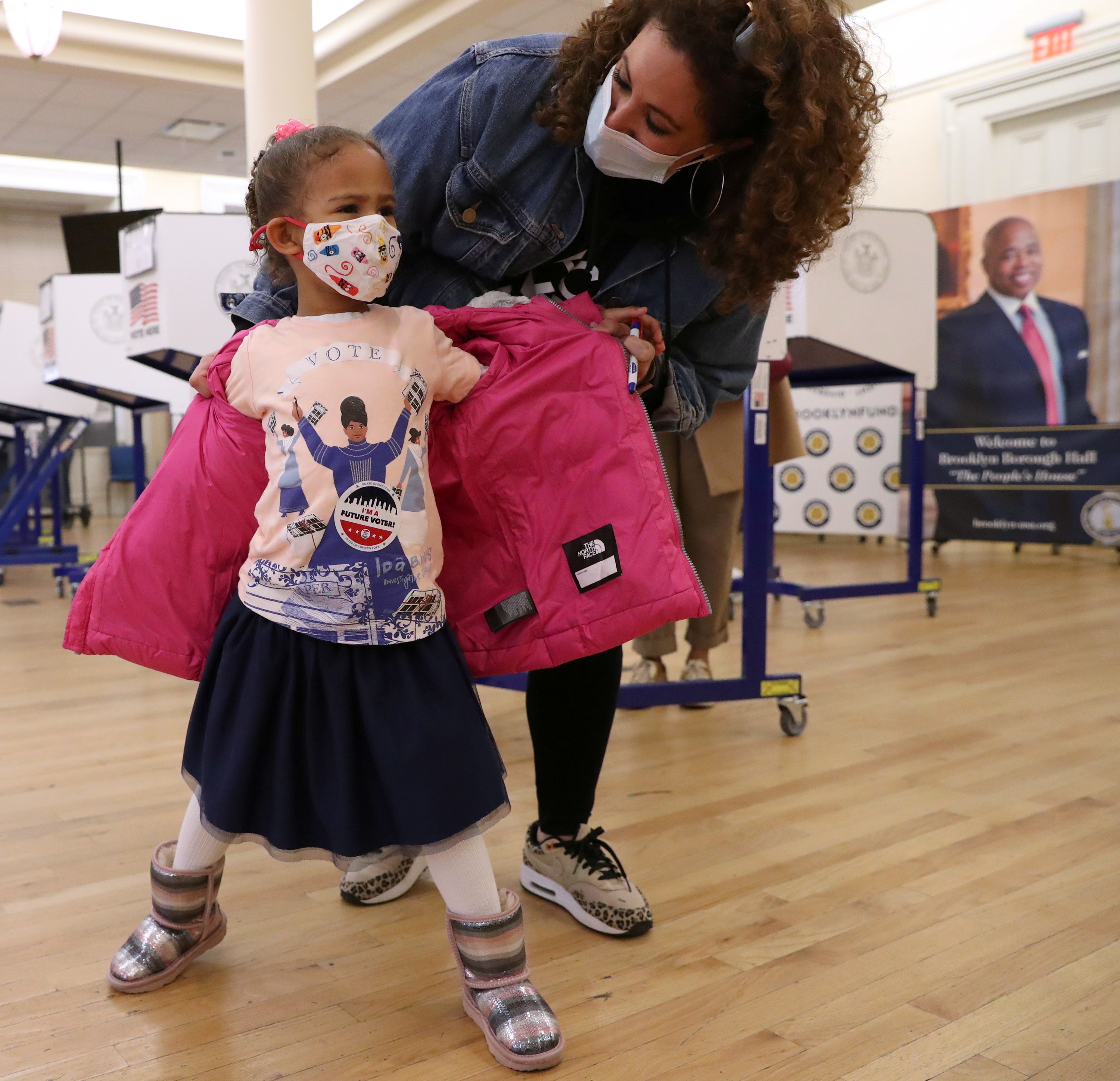 Young girl in pink jacket showing off her shirt. 