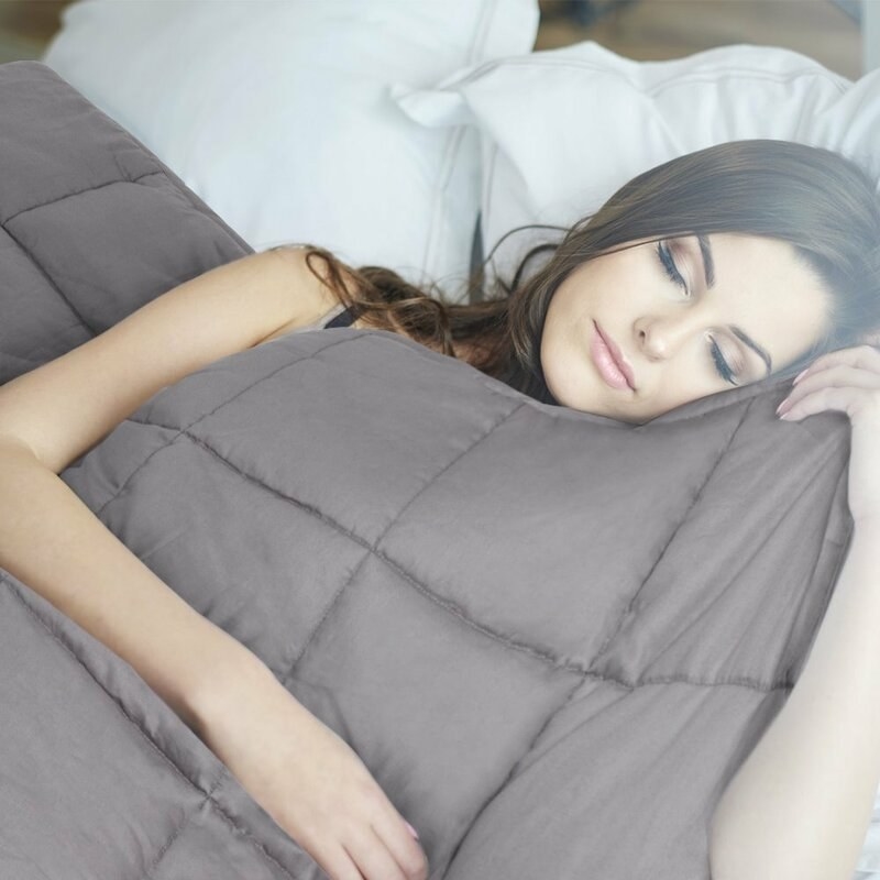 Woman sleeping with gray guilt patterned weighted blanket