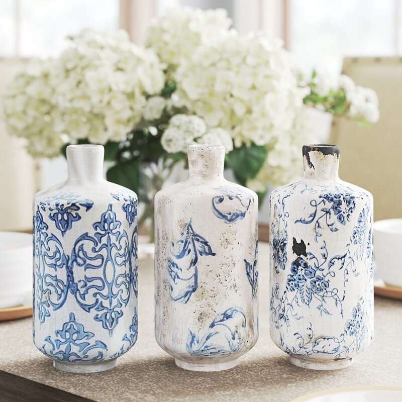 three terracotta vases painted white with indigo designs drawn on