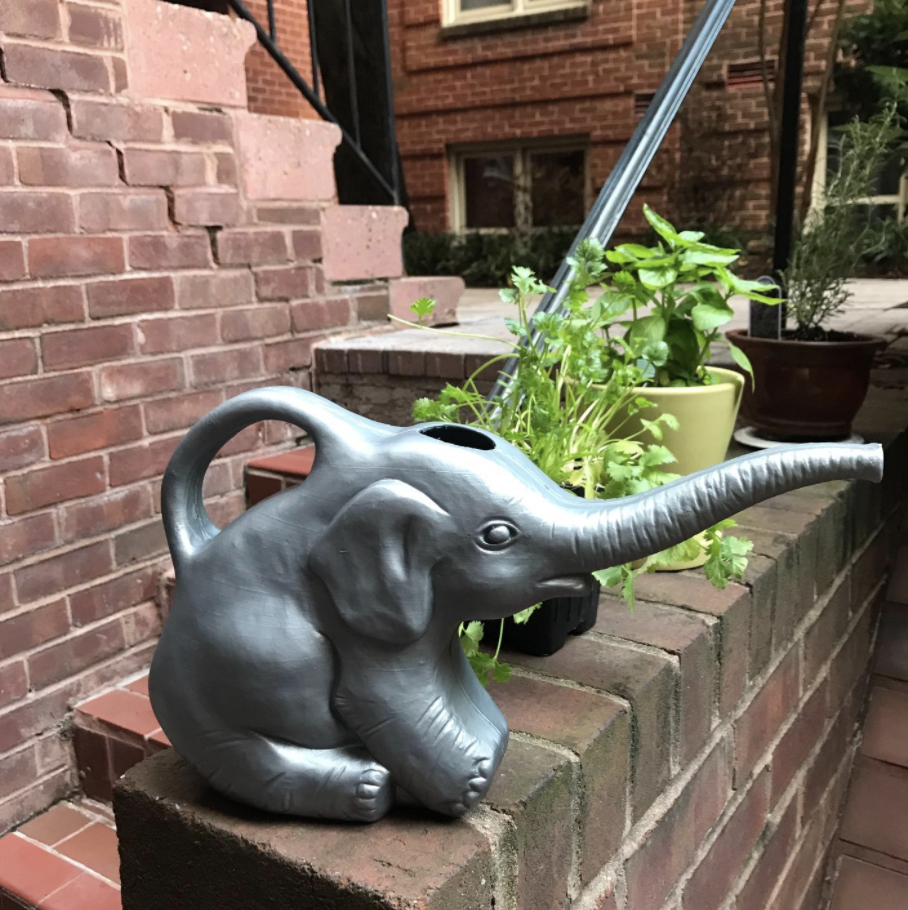 An elephant-shaped watering can next to plants.