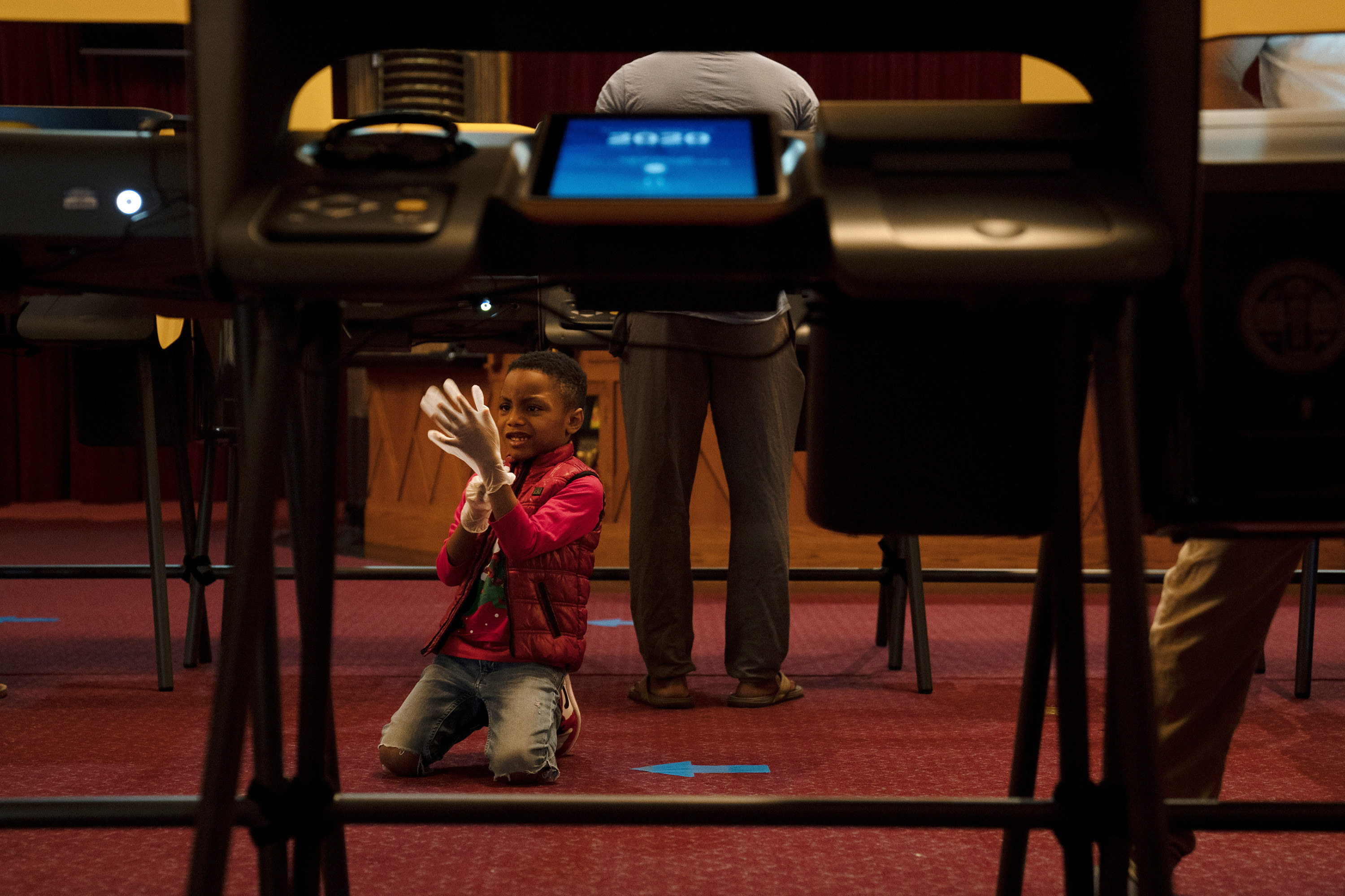 Boy with plastic glove on the floor of a polling place. 