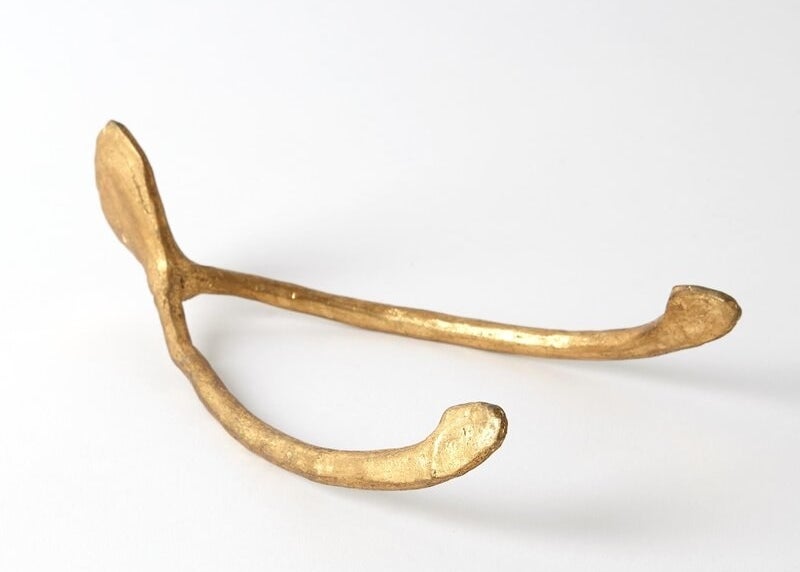 a gold paperweight in the shape of a wishbone