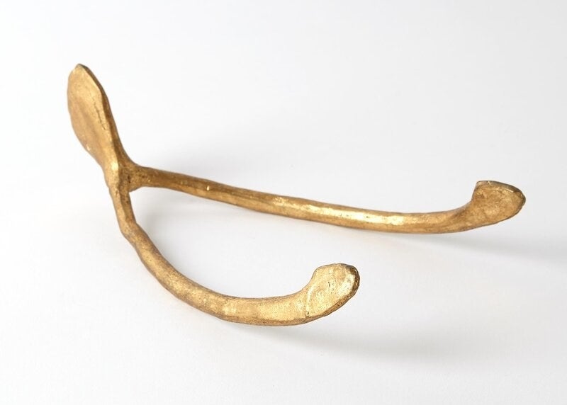 a gold paperweight in the shape of a wishbone