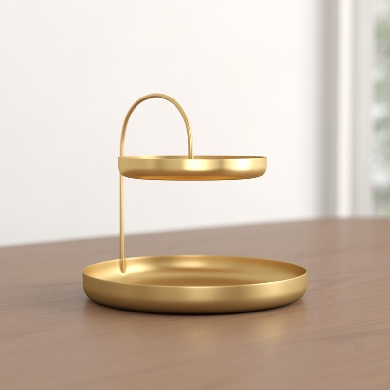 a two-tier gold organizer tray for jewelry on a wooden counter