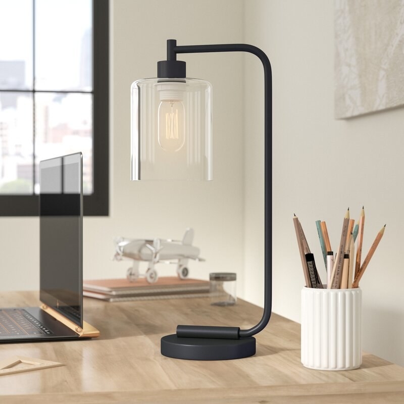 a black industrial lamp with a glass lamp shade on a desk