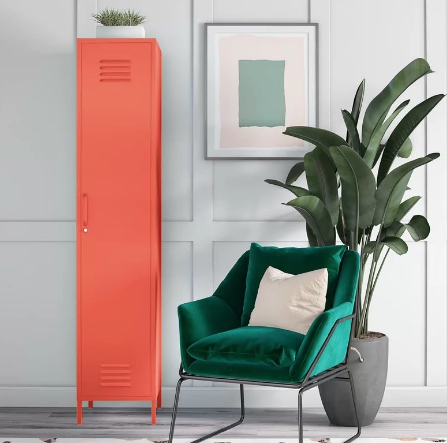 Tall red locker storage cabinet next to green velvet chair and tall indoor plant