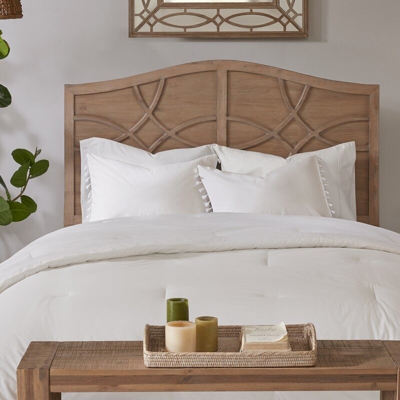 an ivory comforter set with tassels on the pillowcases on a wooden bed