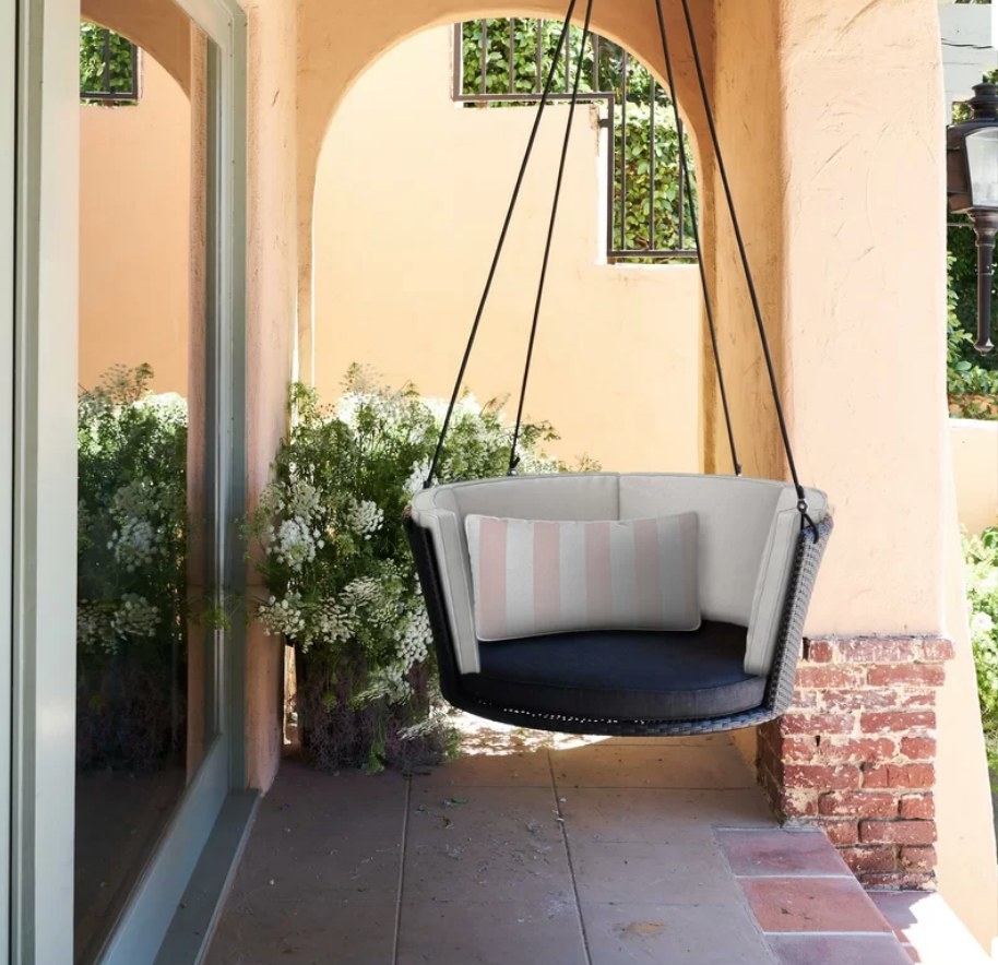Round black porch swing with white cushions along the back and black cushion on the seat