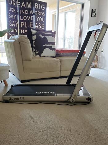 reviewer shows same black treadmill with riser up in their living room