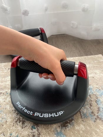 Reviewer holding the black and red push-up bar, showing how comfortable it is 