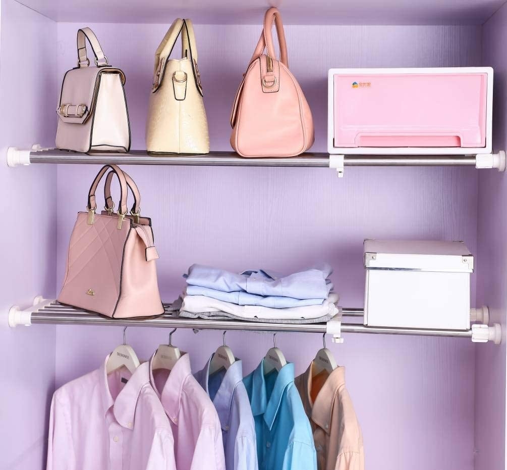 Several shirts hanging from one of the shelf's rods, and boxes and accessories on top of it
