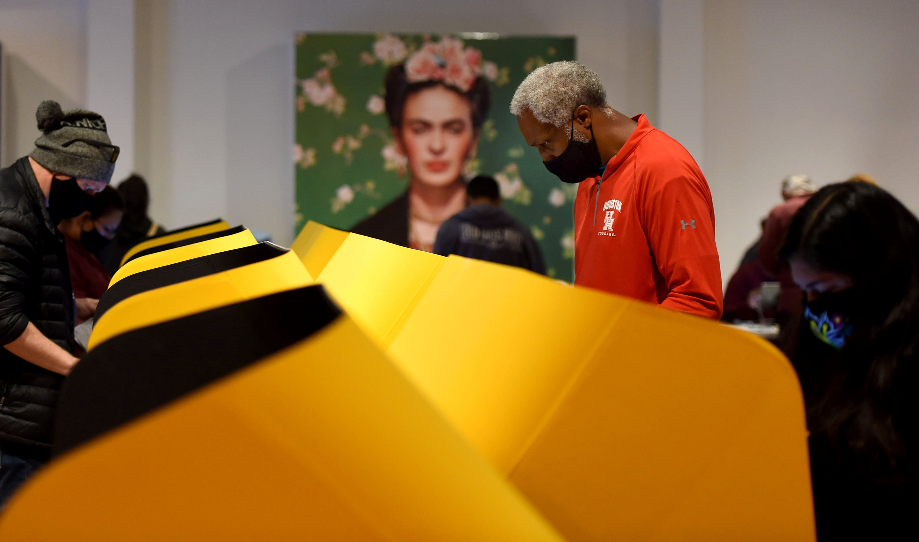 Man voting in front of a portrait of Frida Kahlo. 