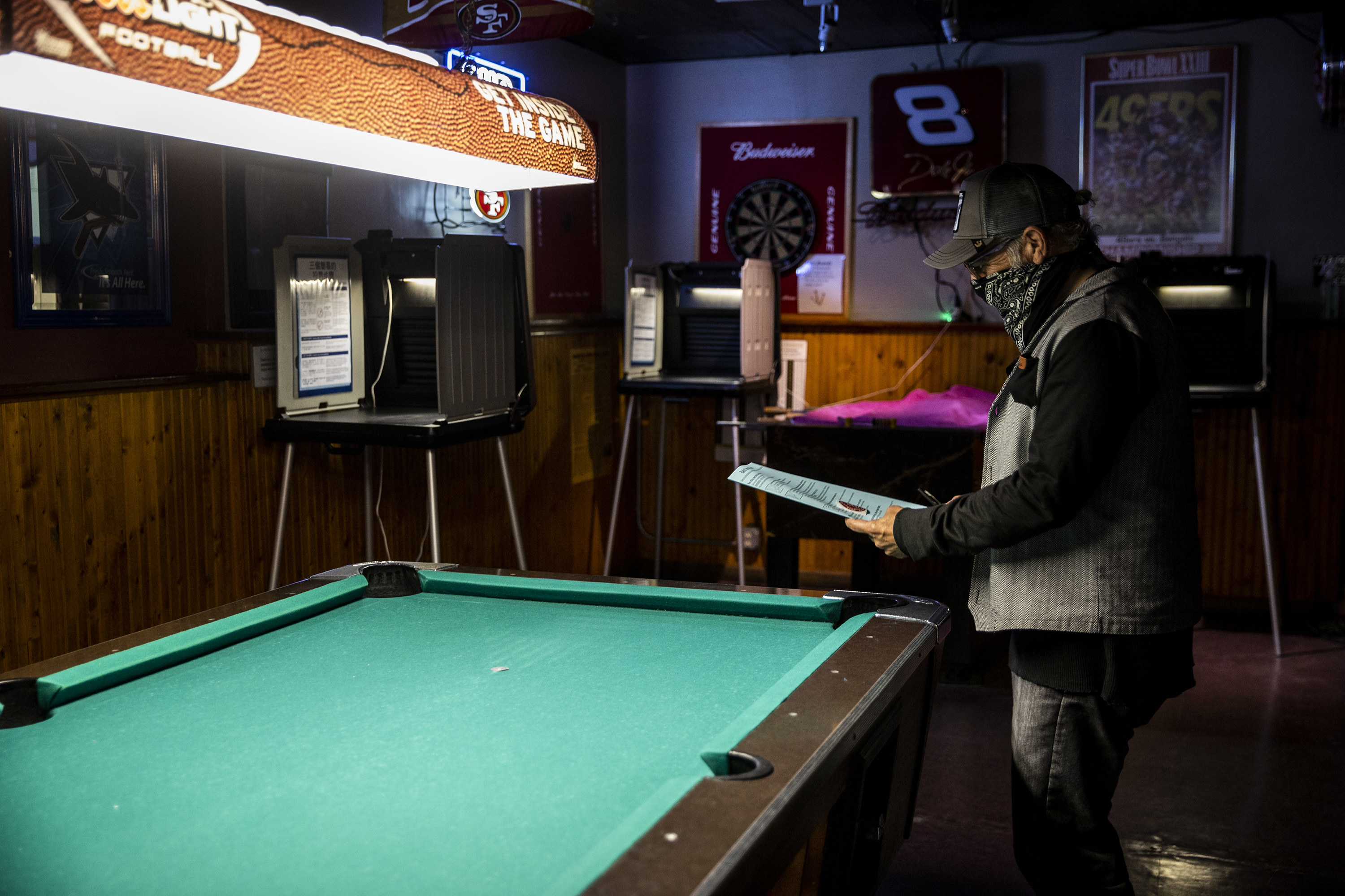 Man reviewing his ballot in front of a pool table. 