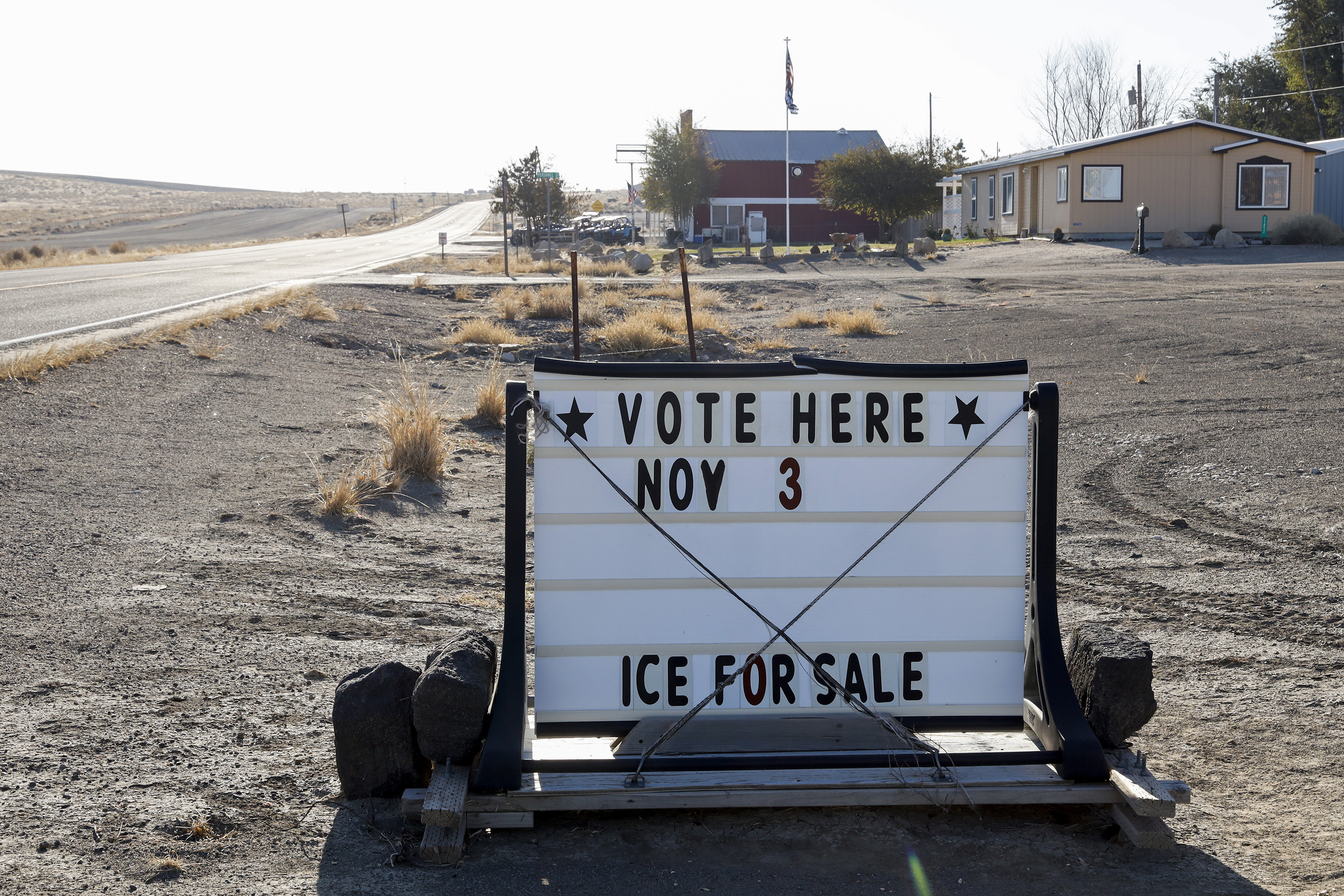 A sign advertising voting on the side of a dusty road. 