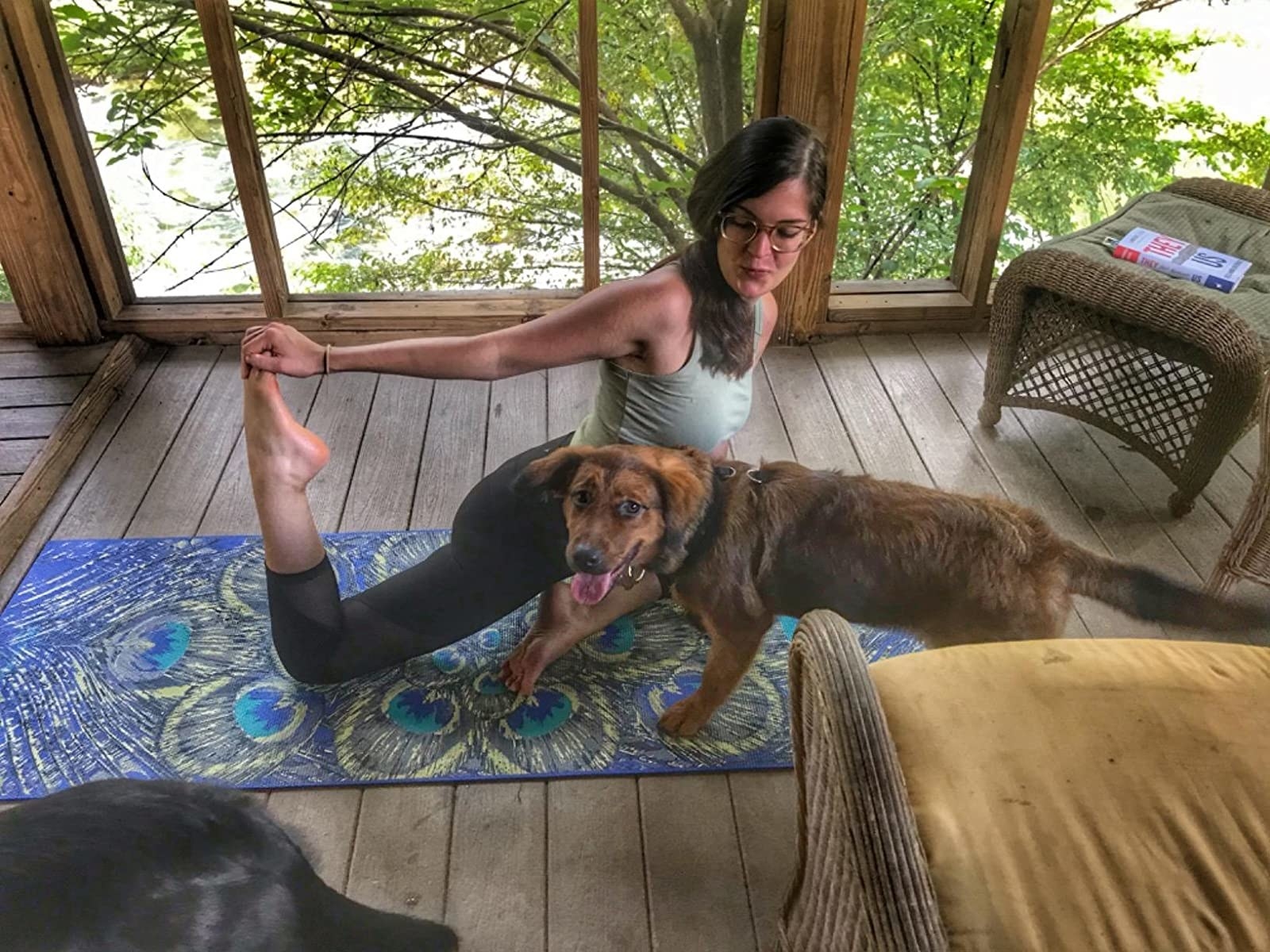 Reviewer flexes foot on peacock-print yoga mat indoors